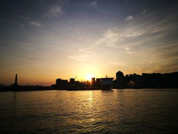 Silhouette of city at waterfront during sunset