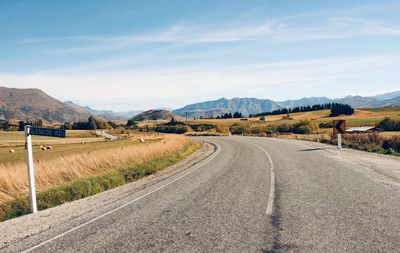 Empty road along landscape against sky