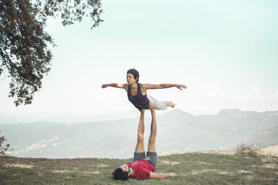Couple doing acroyoga in front of sky