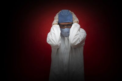 Portrait of person standing against red background