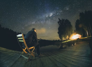 Rear view of man sitting on seat at night