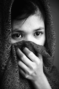 Close-up of young woman covering face with headscarf