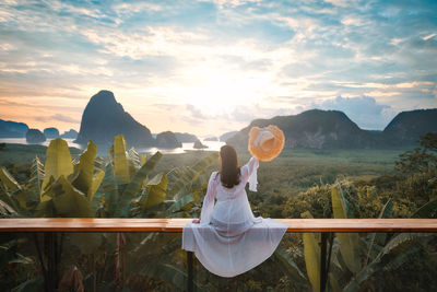 Woman holding umbrella against mountains during sunset