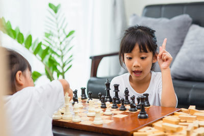 Cute sisters playing chess at home