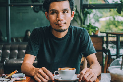 Portrait of young man drinking coffee in cafe