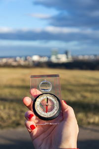 Cropped hand of woman holding navigational compass outdoors