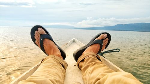 Low section of man relaxing on boat in sea