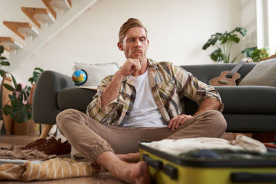 Young woman using phone while sitting on sofa at home