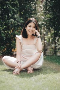 Portrait of smiling young woman sitting on field