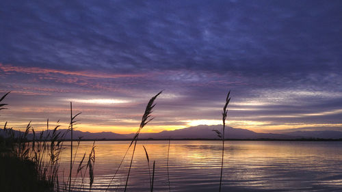 Scenic view of lake against dramatic sky during sunset