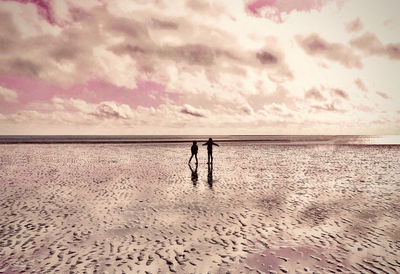 Friends on beach against sky