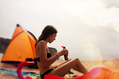 Side view of woman sitting on hammock