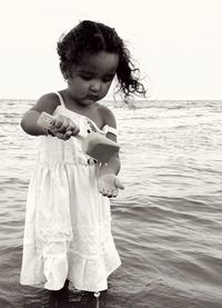 Full length of cute girl at beach against sky