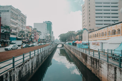 Canal amidst buildings in city against sky