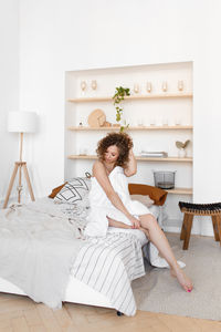Woman sitting on bed at home
