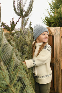 Portrait of young woman standing against trees