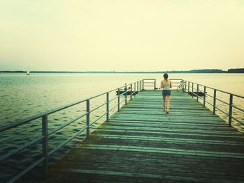 Rear view of man standing on pier