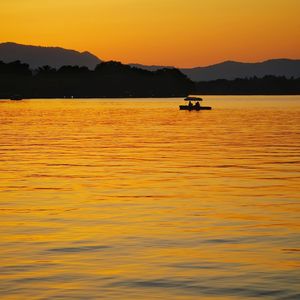 Silhouette boat in sea against sky during sunset