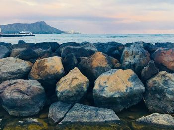 Rocks at sea shore against sky during sunset