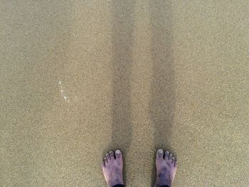 Low section of man standing on sand