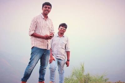 Portrait of male friends standing against sky