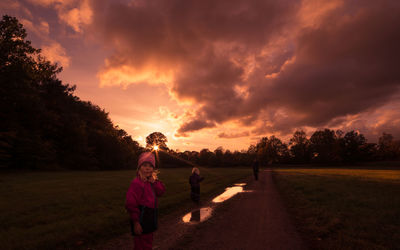 Children playing in park against sky during sunset