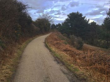 Country road against cloudy sky