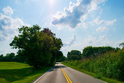 Road amidst trees and field