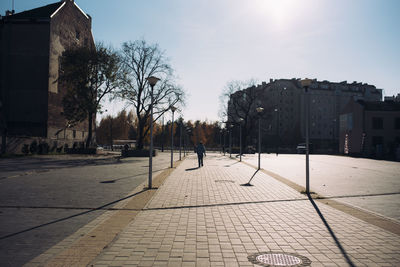 Man walking on footpath amidst buildings in city