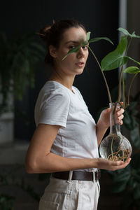 Young woman smiling while standing against plants