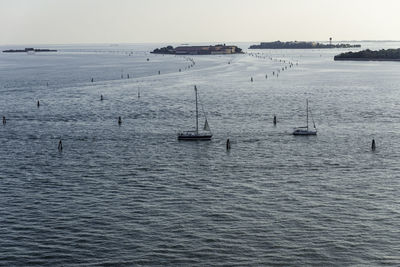 Sailboats sailing in sea against clear sky