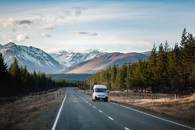 Car on road by mountains against sky