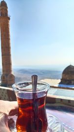 Cropped hand holding turkish tea in glass against sky