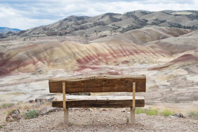 Empty bench on field against mountains