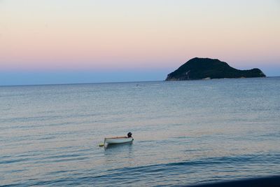 Boat sailing in sea at sunset
