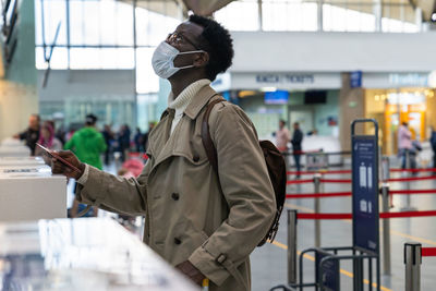 Side view of man using mobile phone while standing on bus