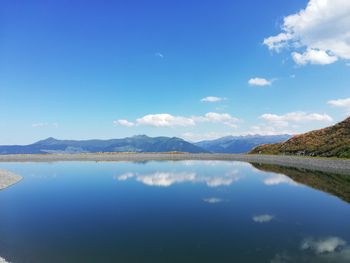 Scenic view of lake and mountains against blue sky