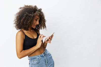 Portrait of young woman standing against white background