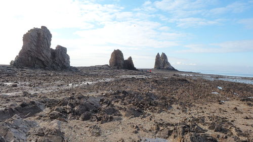 Rock formations on beach against sky