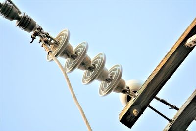 Low angle view of  power line ceramic insulators against clear blue sky