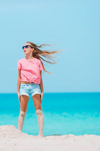 Woman standing at beach against blue sky