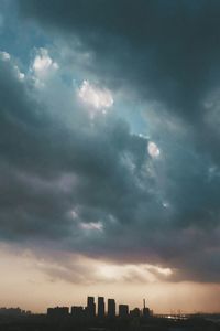 Cityscape against cloudy sky at sunset