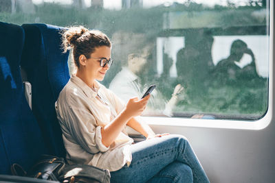 Smiling woman using mobile phone in train