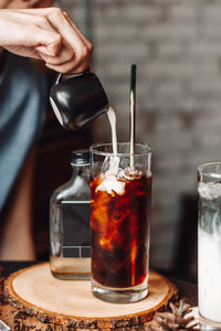 Close-up of hand pouring juice in glass on table