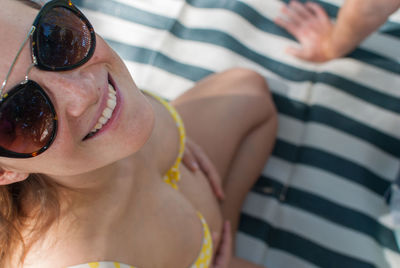 Portrait of a smiling young pregnant woman in a swimsuit on beach towel