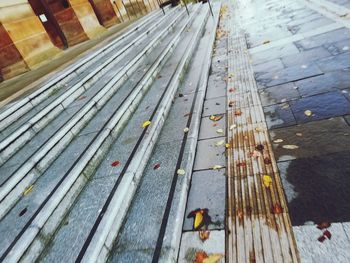 High angle view of wooden bench on footpath
