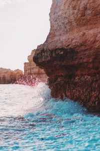 Sea waves splashing on rock formation at beach