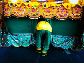 Rear view of man bending amidst curtains