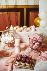 Cupcakes with pink cream and decorated with golden pastry beads on a white tray