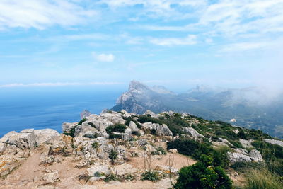 Scenic view of rocky mountain by sea against sky